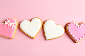 Decorated heart shaped cookies on color background, top view