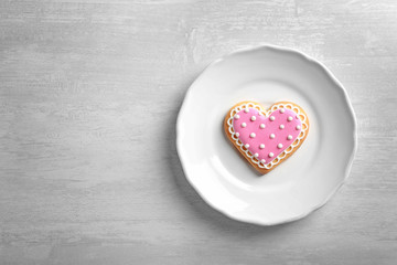 Plate with decorated heart shaped cookie and space for text on table, top view