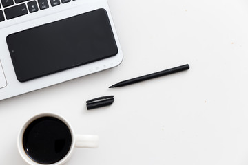 White office desk with laptop mobile phone coffee and pen