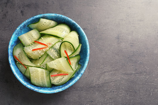 Dish with fresh cucumber salad on  table, top view. Space for text