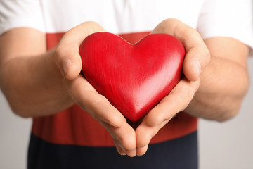 Man holding red decorative heart, closeup view