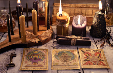 Still life with tarot cards, black candles, key and books on old table. Magic ritual. Wicca,...