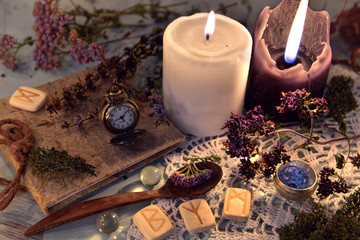 Wooden runes, healing herbs, black and white candles and diary book on lace napkin. Magic ritual....