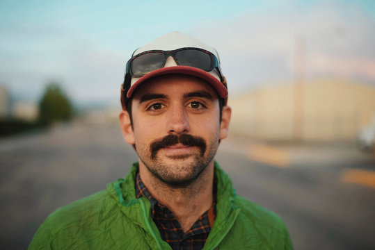 Portrait of smiling man wearing cap standing on road - Powered by Adobe