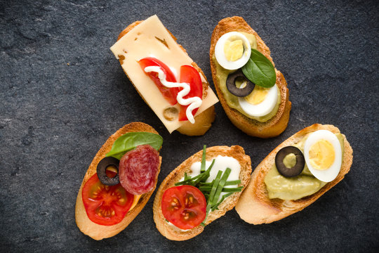 Open faced sandwich canape or crostini on dark stone background closeup. Top view.