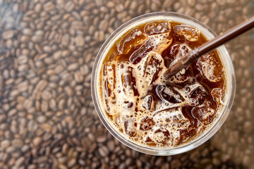 top view glass of iced black coffee on coffee beans background