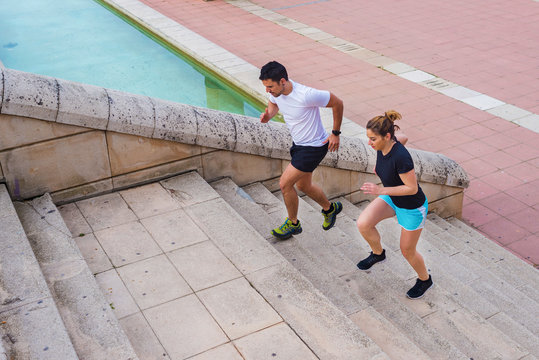 High Angle View Of Couple Running On Steps At Park In City