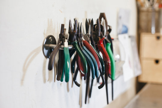 Close-up of colorful pliers hanging on rack by wall in workshop