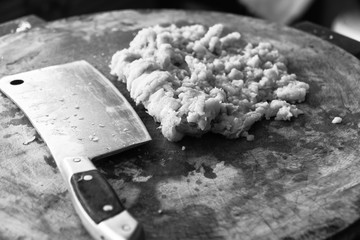 chopping pork. Placed on a wooden chopping board to cook for the next step.back and white
