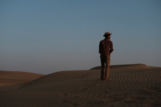 Rear view of man standing at Thar Desert against clear sky during sunset