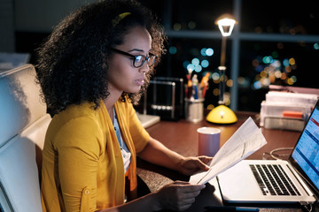 Side view of businesswoman with curly hair analyzing financial bills in office
