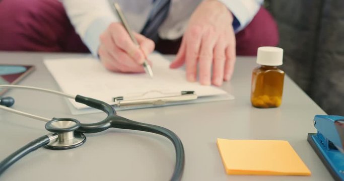 Medical Professional Filling Medical Form In Clipboard At Desk 4K