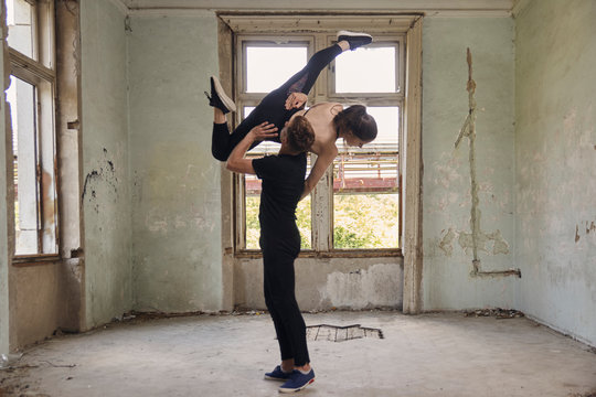 Man lifting ballerina while dancing in old building