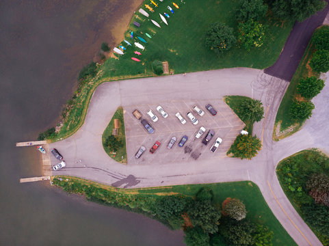 Aerial view of boats moored at harbor while cars parked in parking lot by lake