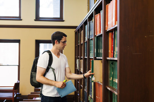 Student searching for books in shelf at library