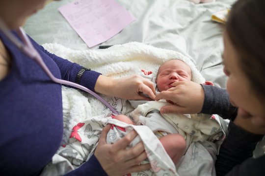 Midwife examining newborn baby at home