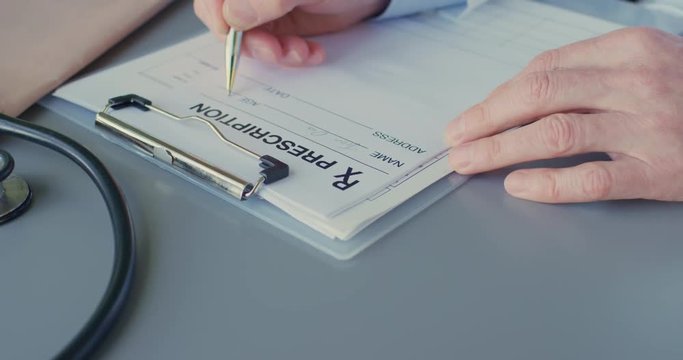 Doctor Writing Rx Prescription On Clipboard At Desk 4K