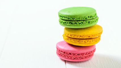 Macaroon cake red and yellow and green on a white wooden table on a white background.