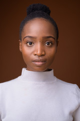 Face of young beautiful African woman against brown background