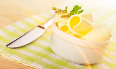 Sliced fresh butter in white bowl on checkered napkin