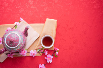 teapot, cup of tea and cherry blossom on red tablecloth background, concept of Chinese new year background. top view.