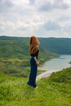 A beautiful girl tourist enjoys nature next to a mountain river