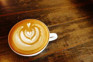 a cup of latte art coffee on wooden background