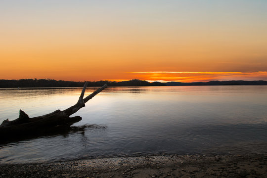 Beautiful orange yellow and red sunrise sunset over calm water of Dale Hollow Lake, Tennessee. Silhouette of a log reflected in the water. Concepts of travel, vacation