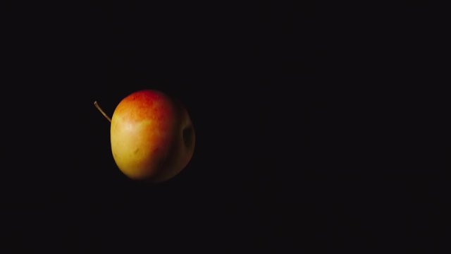 SLOW MOTION: Red apple flies up and falls down on a black background