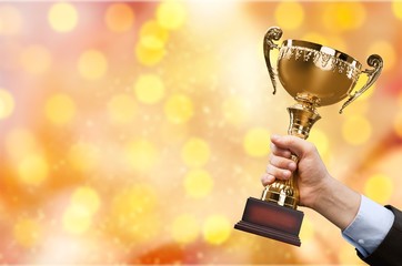 Hand of kid holding champion cup on glossy background