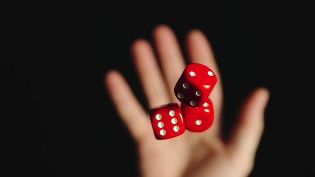 SLOW MOTION: Three red dice are tossed and caught - Top View