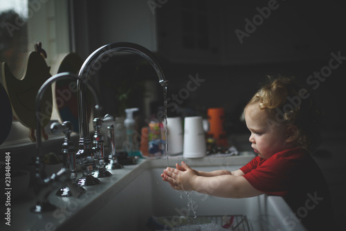 Side view of girl washing hands in sink at home