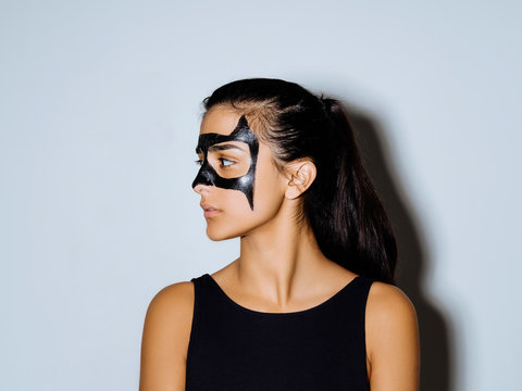 Close-up of woman with face paint looking away standing against wall