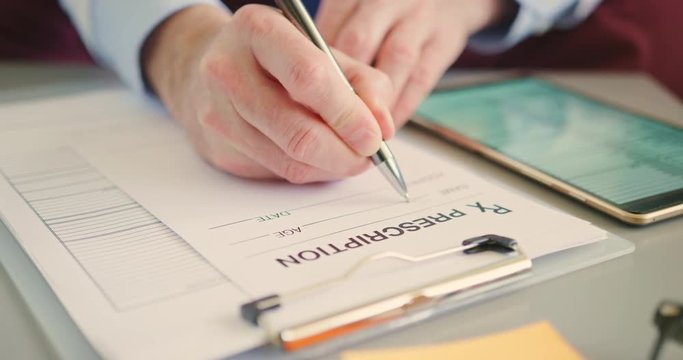 Medical Professional Writing RX Prescription At Desk 4K
