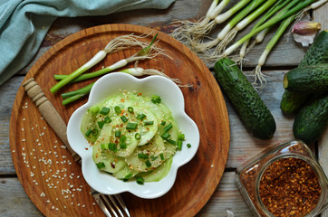 Fresh cucumber cut with chives in a white bowl on a wooden board