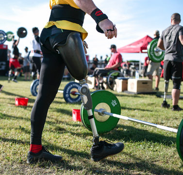 Low section of male athlete with prosthetic leg standing by deadlift in park