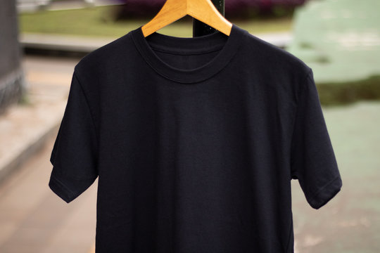 Black Short Sleeve T Shirt On Wood Hanger In Outdoor. Ready For Your Mock Up Design Or Presentation Your Design Project.