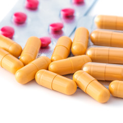 Red and yellow tablets and blisters scattered on a white background.