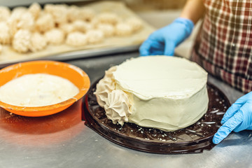 Pastry chef in gloves preparing meringue cake and desserts. Production of confectionery