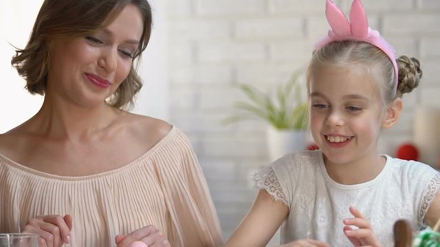 Mother and kid packing dyed Ester eggs in box, giving high-five to each other