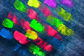 The texture of denim with strokes of fluorescent gouache color paint. Abstract background jeans