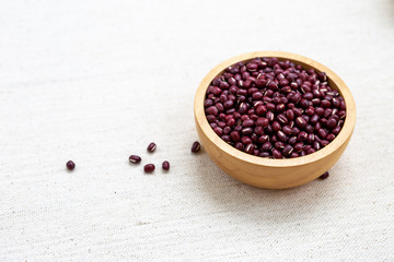 Fototapeta na wymiar Small raw red bean in round wooden bowl on canvas background, organic bean, vegetarian food