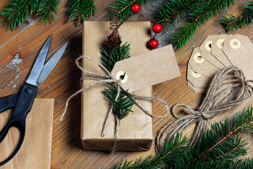 High angle view of Christmas present with labels and strings by pine needles on wooden table
