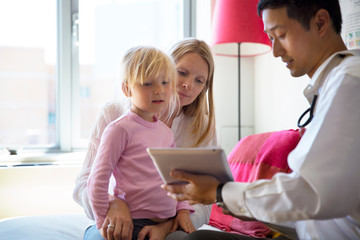 Doctor showing tablet computer to family