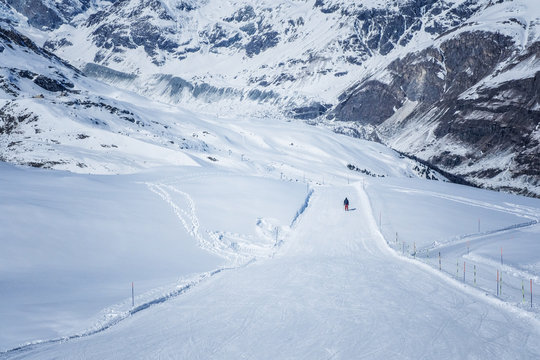 Skiers skiing down the mountain on a beautiful sunny day in Switzerland.