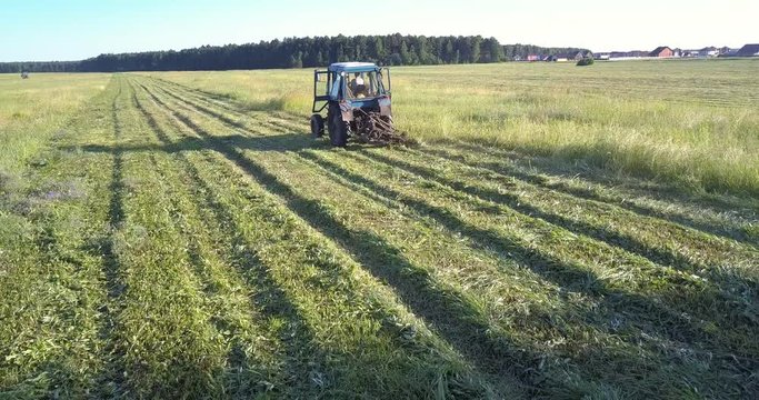 machinery with mower moves along field cutting off grass
