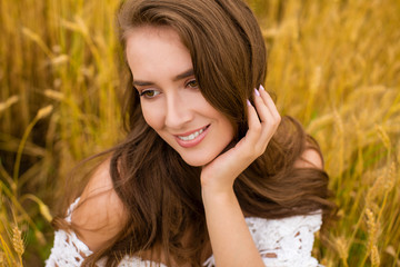 Portrait of a young girl on a background of golden wheat field