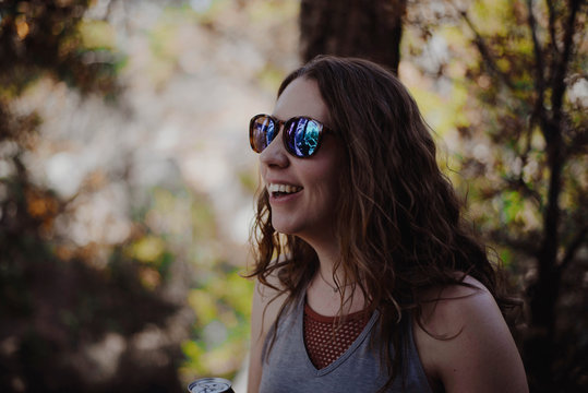 Close-up of happy woman wearing sunglasses while standing in forest
