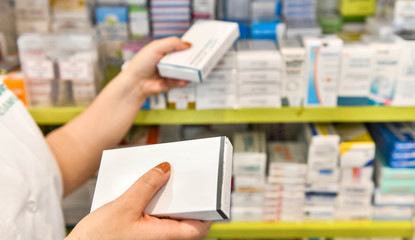 Pharmacist holding medicine box in pharmacy drugstore.