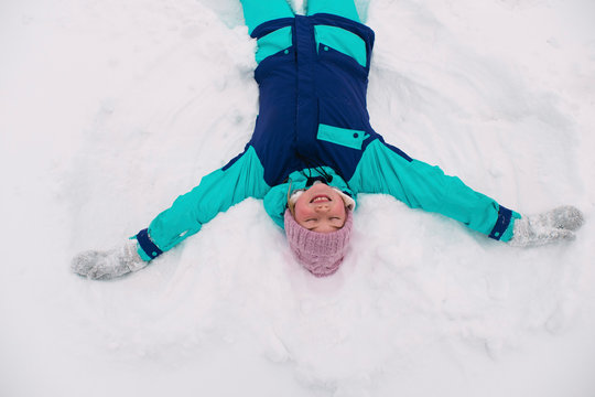 High angle view of woman with eyes closed making snow angel on field